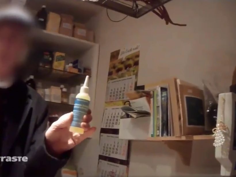 Älterer Herr (geblurrt) hält ein kleines Plastikfläschchen mit Etikett hoch.