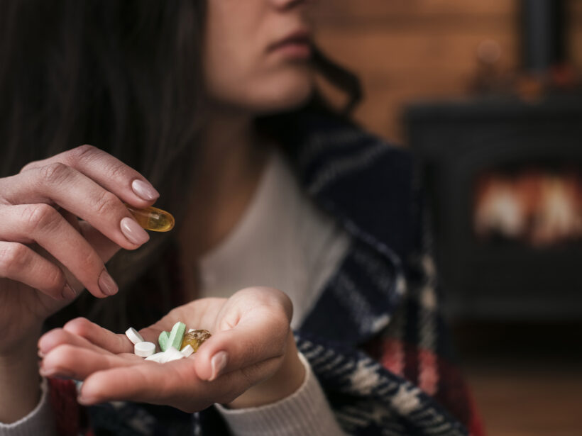 Nahaufnahme Frau mit diversen Kapseln und Tabletten in ihrer Hand